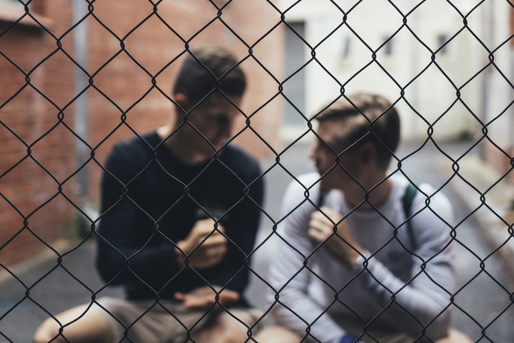 two young men talking behind fence